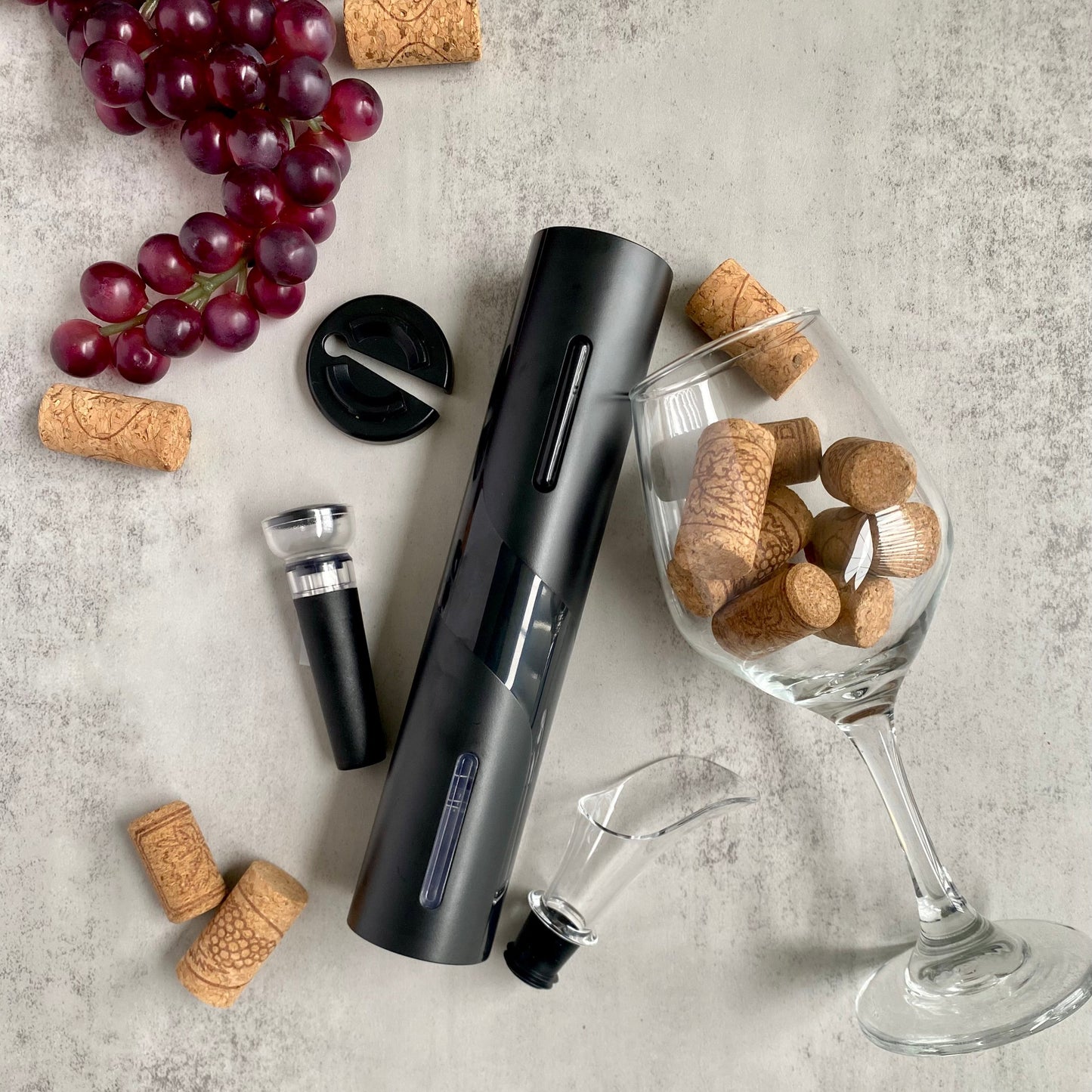 Black electric wine opener set with wine corks, wine glass, and grapes