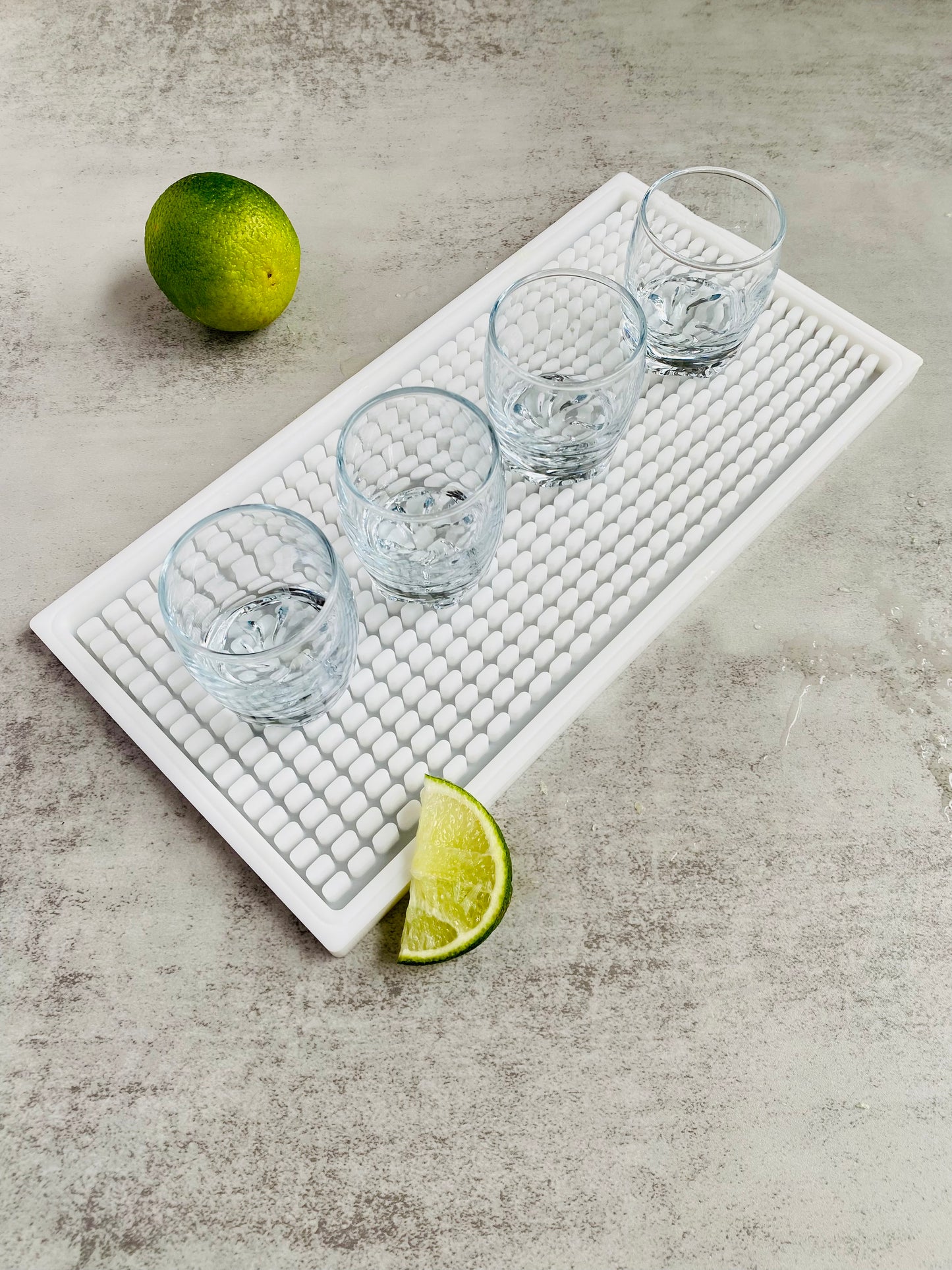 Shot glasses sitting on a white bar mat with limes 